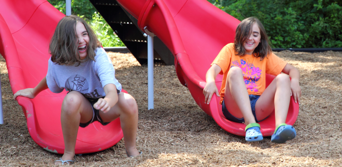 two girls sliding down a side at vangelli park